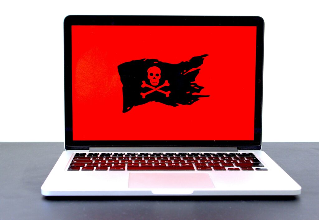 Laptop screen displaying a malware warning with a skull and crossbones symbol, representing cyber threats to businesses.